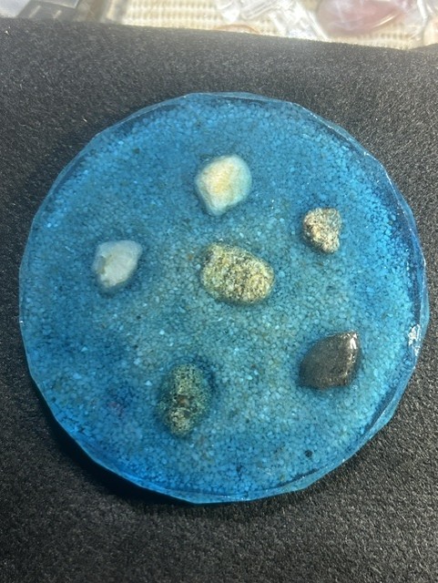 Blue resin coaster with embedded stones.