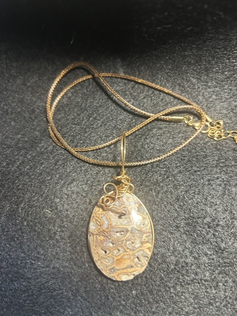 Pendant necklace with intricate stone design.