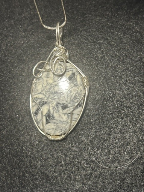 Wire-wrapped stone pendant on gray background.